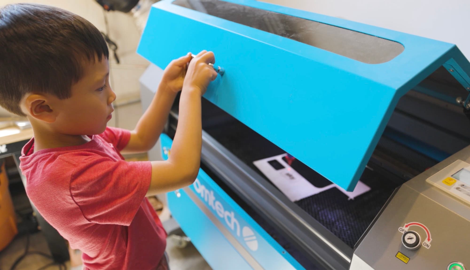 A Forge student operating the laser cutter at the Builder rank.